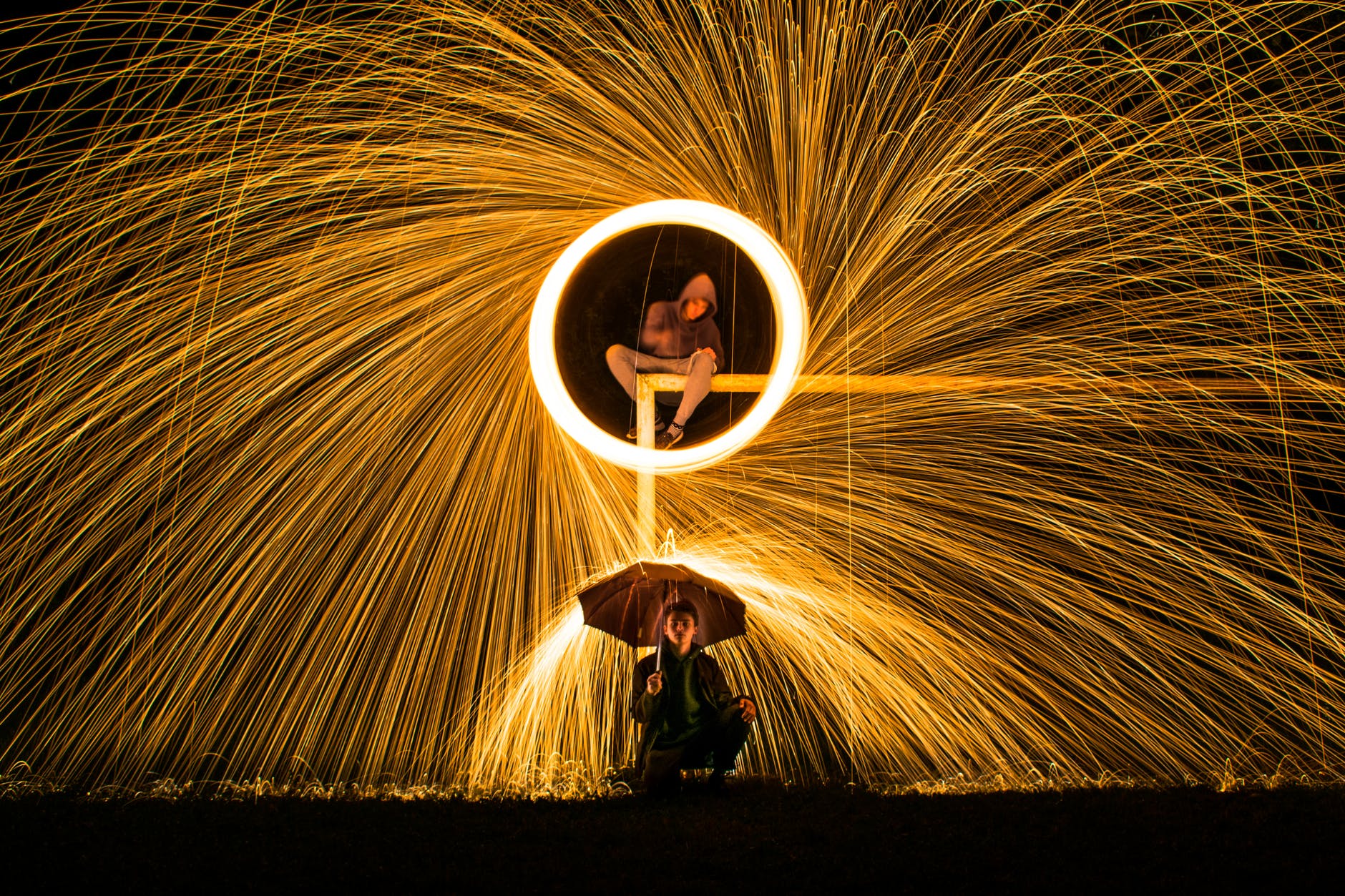 time lapse photography of person making firework spark under person holding umbrella during nighttime